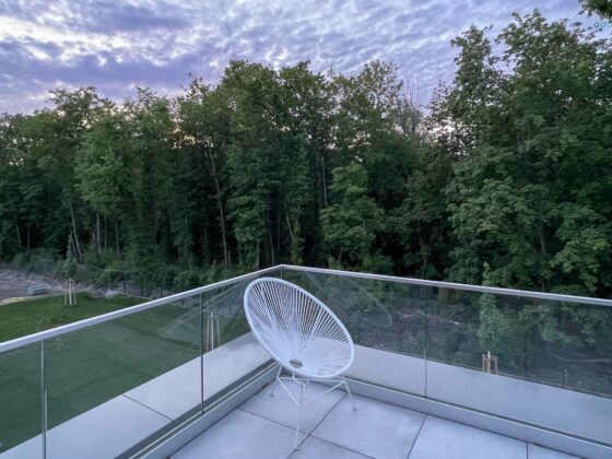 Acapulco chair on balcony overlooking forest and sunset