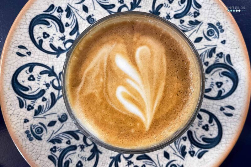 cup of coffee with heart of foam in blue pattern plate