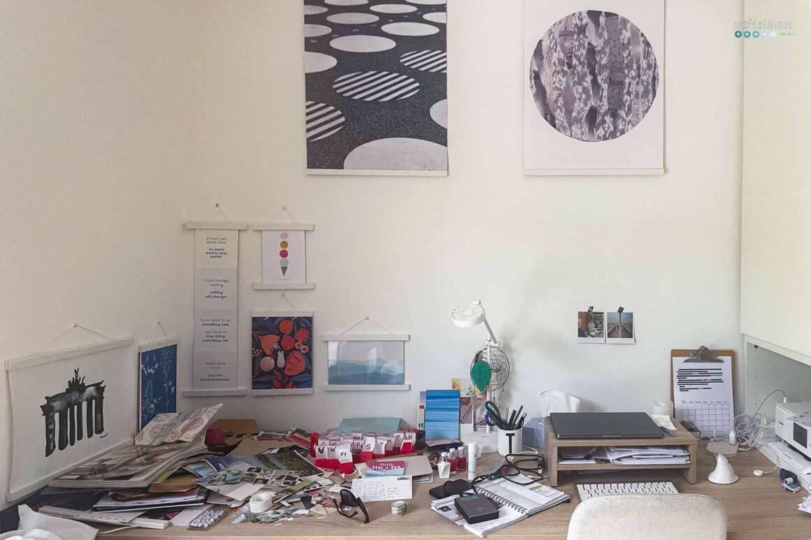 a messy desk, pictures above on the wall