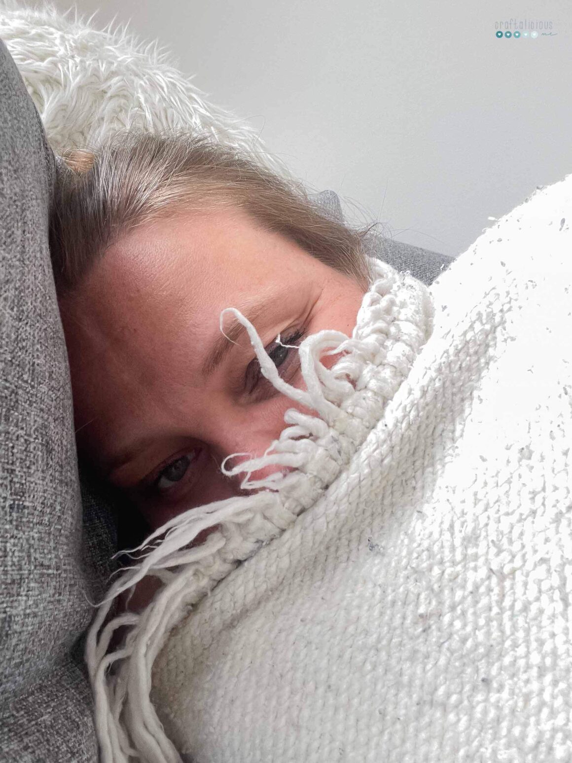 napping person in white wool blanket, face partly covered.