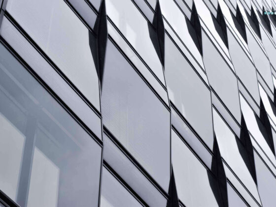 a facade of windows on a gray day. the front is not flat but has different angles.