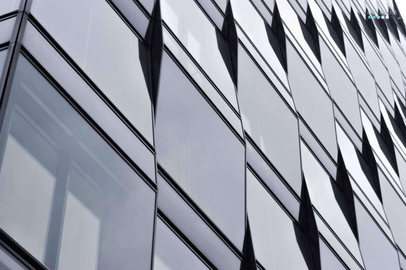 a facade of windows on a gray day. the front is not flat but has different angles.