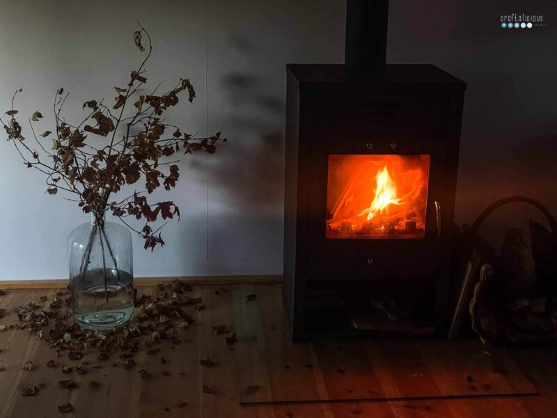 cozy fireplace in the semi dark to the left a vase with fallen leaves